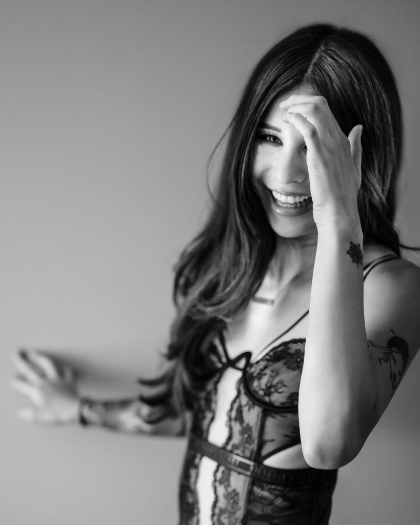 A woman in lingerie laughing have a great time in her boudoir session.