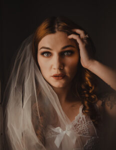 A woman is wearing a wedding dress and veil for her Wedding bridal boudoir shoot