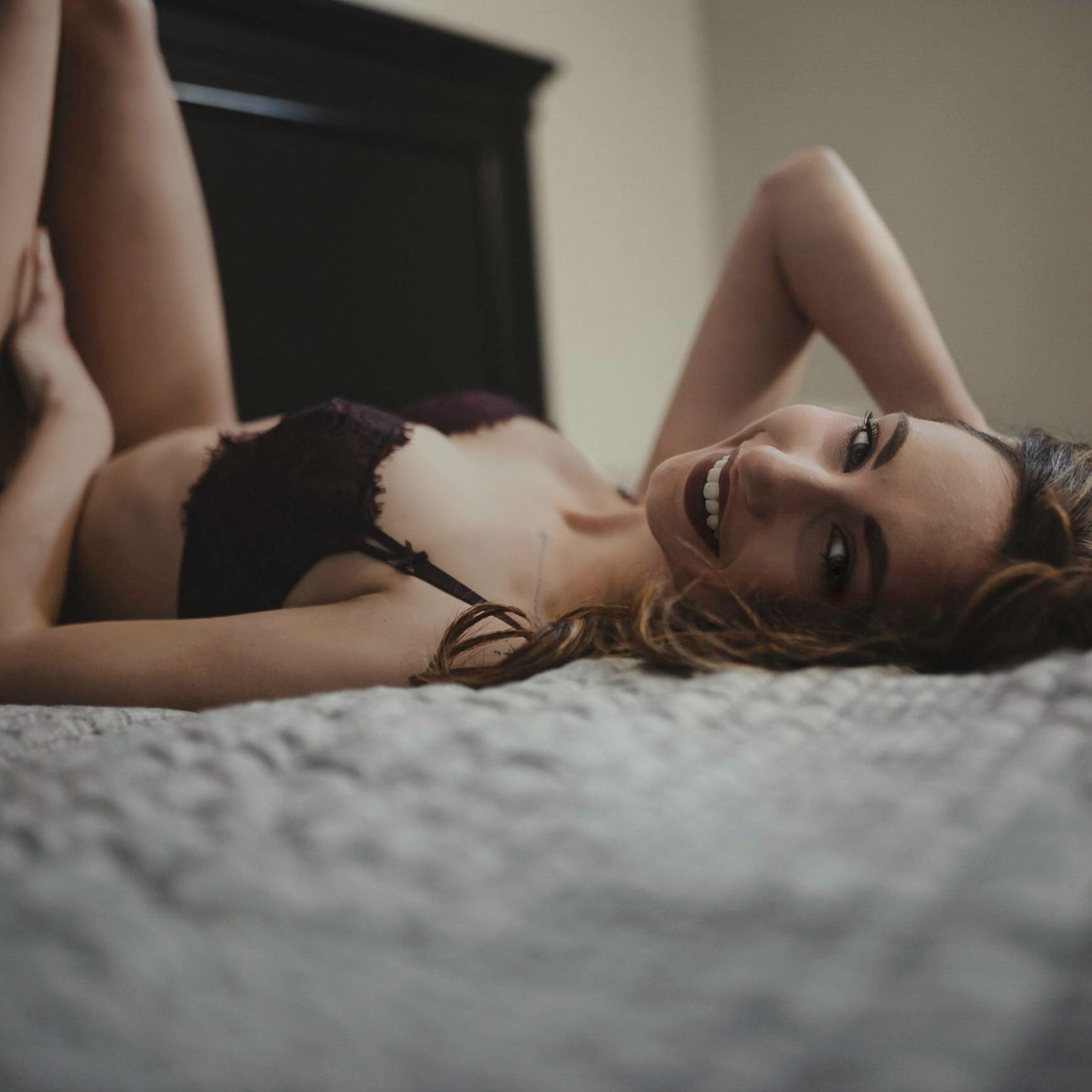 a happy woman on a bed in lingerie smiling